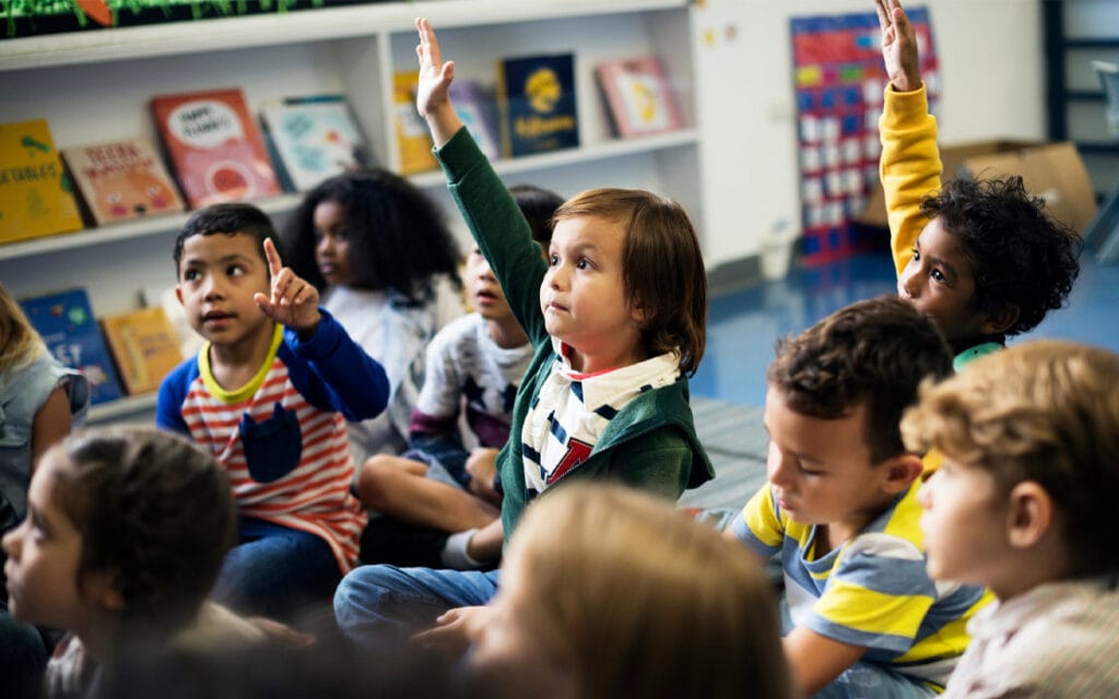 Preschool children participating in circle time at a bilingual classroom, building language and cognitive skills through daily interaction.